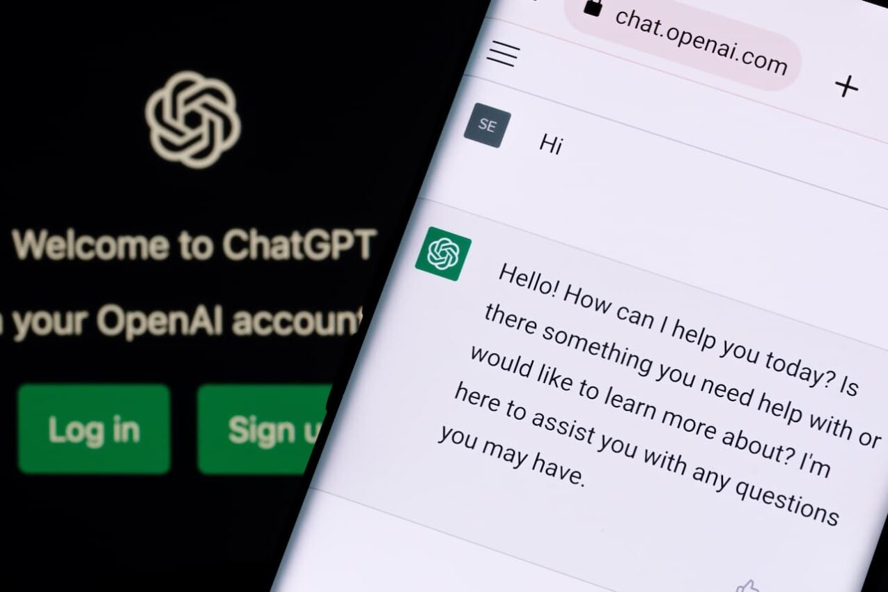 A imagem mostra um celular em diálogo com a IA e ao fundo a logo da OpenAI/ChatGPT.